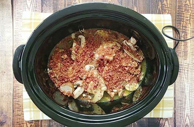 Chicken and wild rice casserole ingredients in a black Crockpot