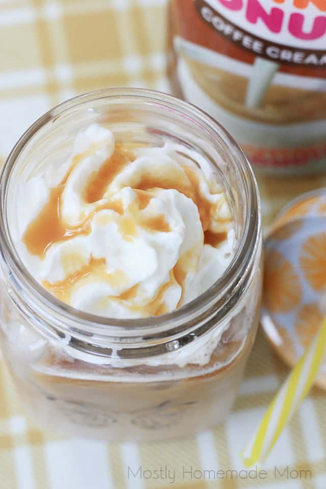 Iced latte in a mason jar with whipped cream and caramel on top