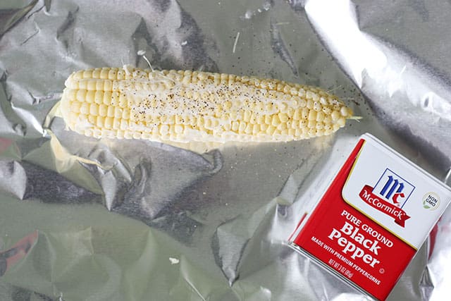 Corn on the cob on foil with butter and pepper