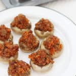 Sausage stuffed mushrooms on a white serving platter