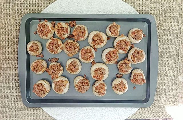 Sausage stuffed mushrooms on a grey cookie sheet