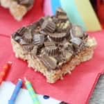 Reese cup rice krispie treat square on a red napkin with birthday candles in front