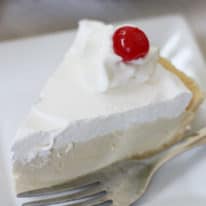 A slice of root beer float pie on a white plate with a fork