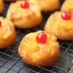 A pineapple upside down cupcake on a wire rack on a cookie sheet