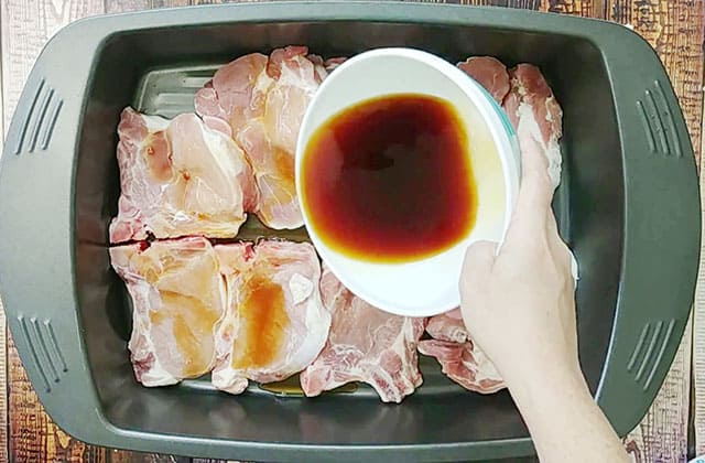 Pouring marinade over pork chops in a roasting pan