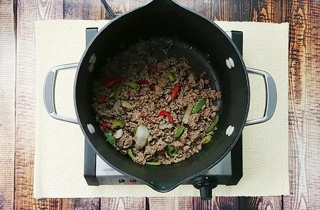 Cooked ground beef, peppers, and onions in a large pot