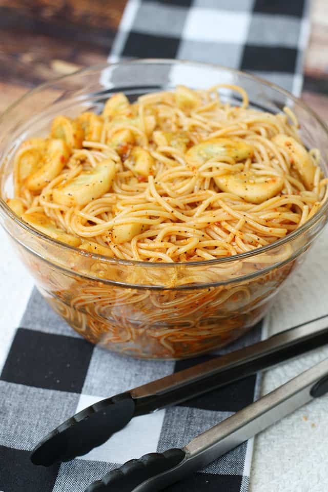 Spaghetti salad in a glass bowl on a black plaid placemat