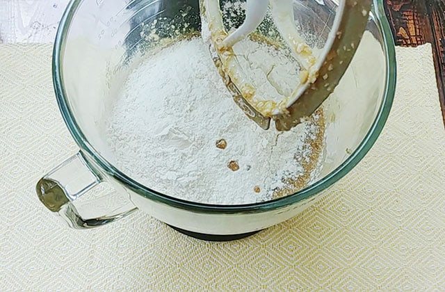 Adding flour to the cookie batter in a stand mixer