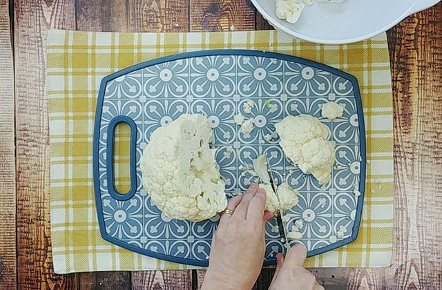 Chopping a head of cauliflower on a blue cutting board