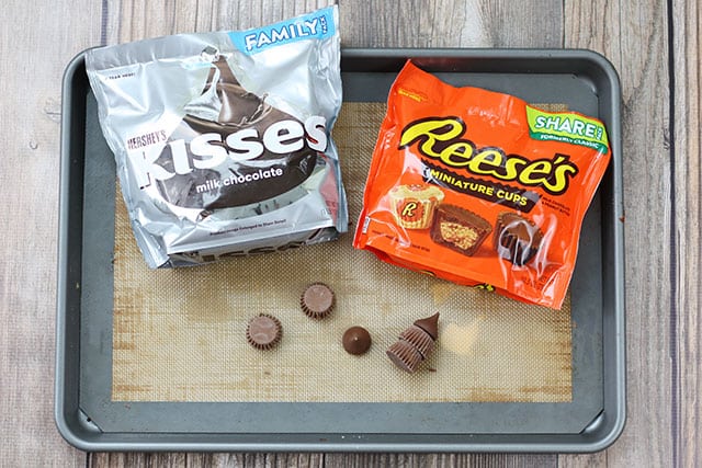 A bag of Hershey Kisses and Reese's peanut butter cups on a cookie sheet