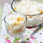 Ambrosia salad in a glass dessert dish with a fork next to it