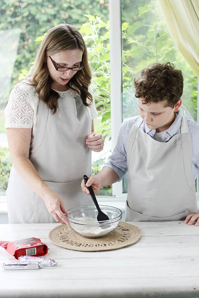 A mother and son stirring dry ingredients in a glass bowl
