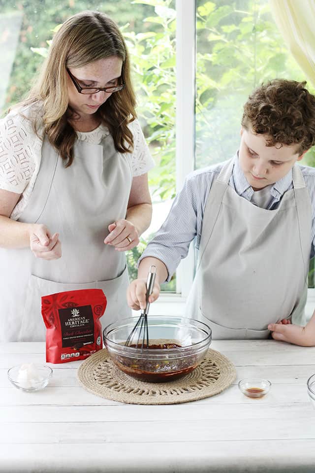 A mother and son whisking brownie batter in a glass mixing bowl