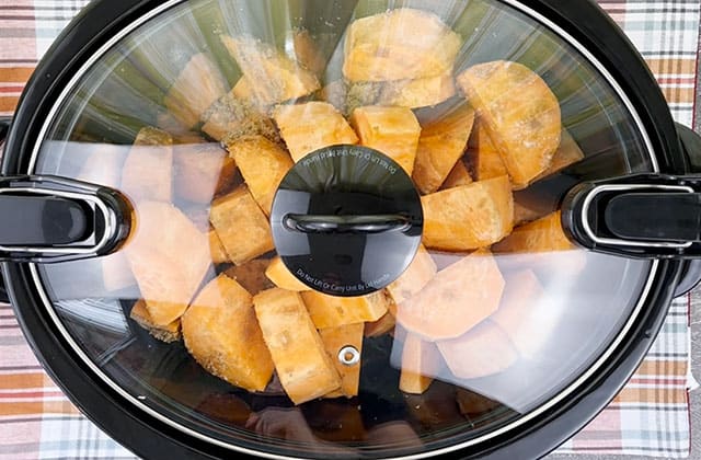 Crockpot sweet potato casserole cooking in a slow cooker with the glass lid on