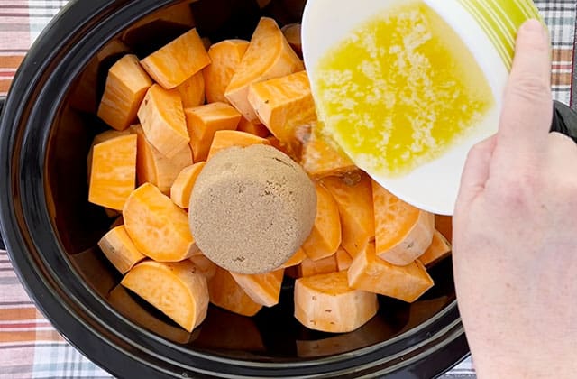 Sweet potatoes, brown sugar, and melted butter in a black crockpot